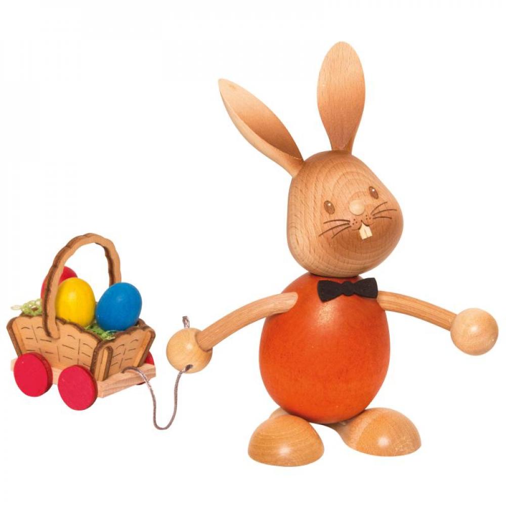 Wooden rabbit Stupsi with a red shirt pulls a small cart behind him with colored eggs on it.